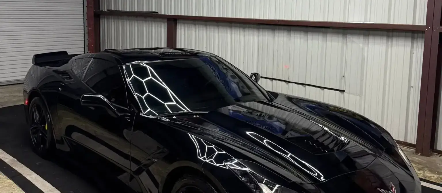 Black Corvette under shop lights after auto detailing in Houma, LA