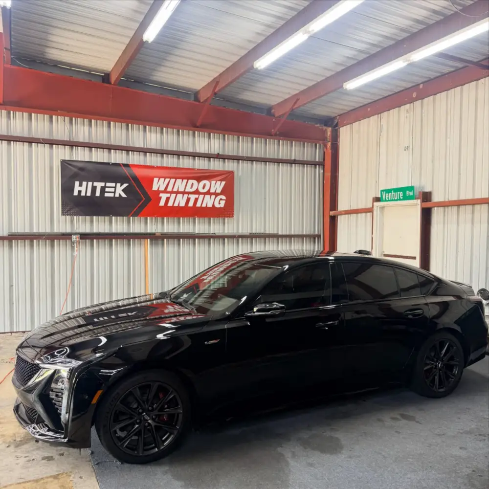 Black Cadillac CT5-V with tinted windows under the HITEK Window Tinting banner inside the South Side Detail And Tint shop in Houma, LA